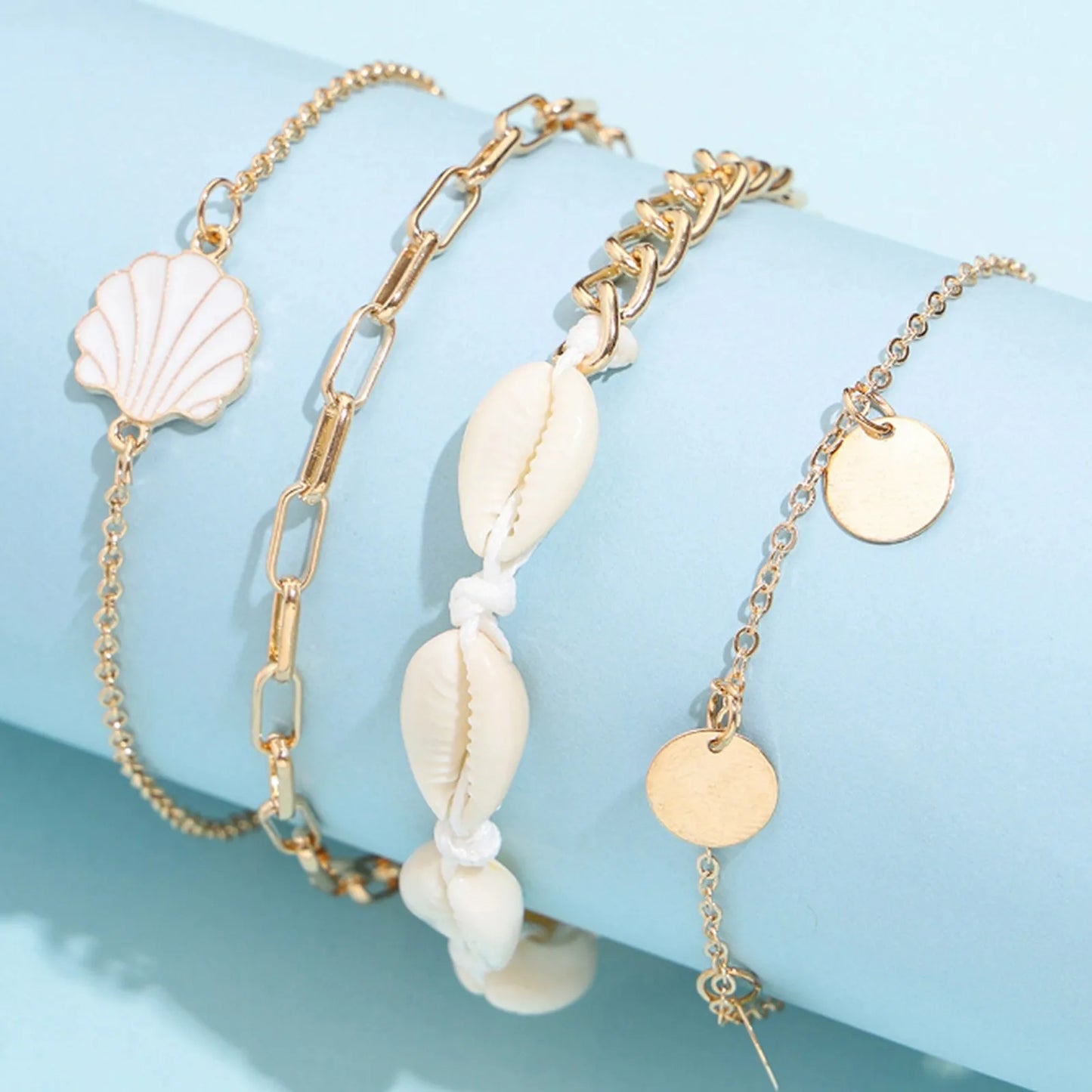"Close-up of 4-piece anklet set featuring pearl and scallop charms"